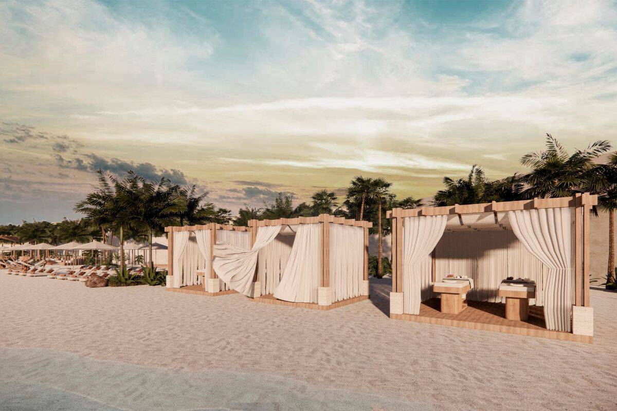 Drei hölzerne Pavillons mit weißen Vorhängen stehen an einem Sandstrand, im Inneren sind Massageliegen erkennbar, im Hintergrund Palmen und Abendhimmel.