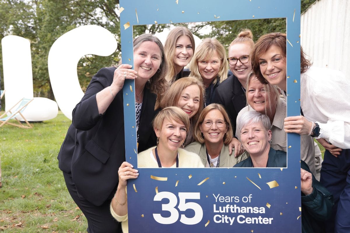Eine Gruppe lächelnder Frauen hält gemeinsam einen blauen Bilderrahmen mit der Aufschrift 35 Years of Lufthansa City Center vor sich in die Kamera.