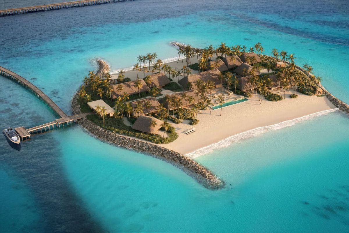 Luftaufnahme einer tropischen Insel mit strohgedeckten Villen, Palmen, weißem Sandstrand, einem langen Holzsteg und einem Boot im türkisfarbenen Ozean.
