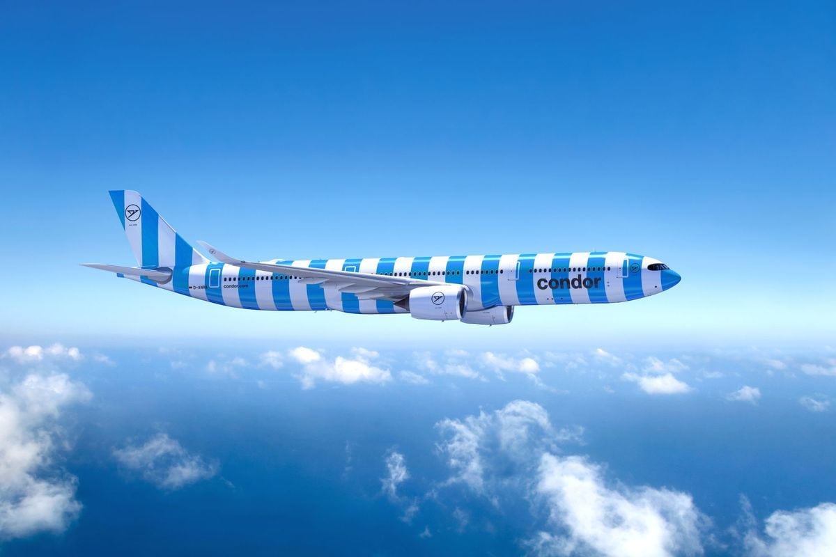 Ein Passagierflugzeug der Fluggesellschaft Condor mit blau-weißer Streifenlackierung fliegt in Reiseflughöhe über einer geschlossenen Wolkendecke am Himmel.