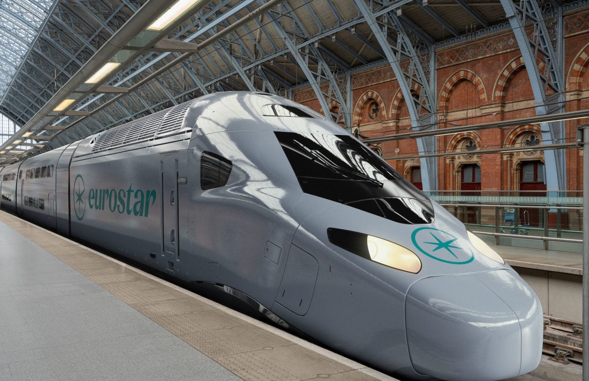Ein grauer Eurostar-Hochgeschwindigkeitszug steht an einem Bahnsteig in einem Bahnhof mit historischer Backsteinfassade und einer hohen Stahl-Glas-Konstruktion.