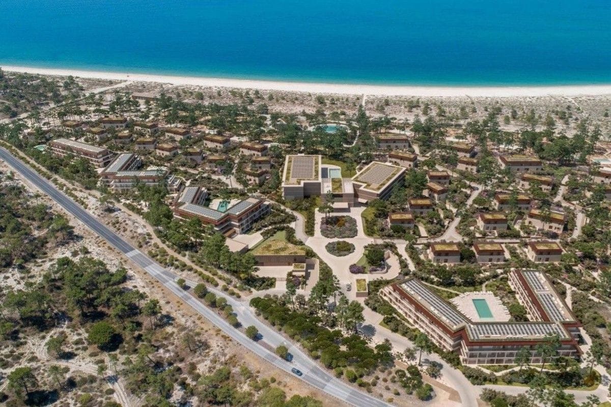 Luftaufnahme einer weitläufigen Hotelanlage mit mehreren Gebäudekomplexen, begrünten Dächern und Pools in einer Küstenlandschaft direkt am Sandstrand.