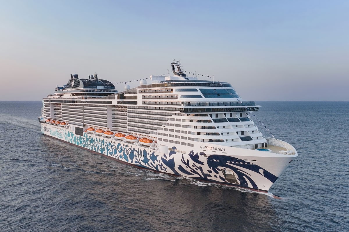 Ein modernes Kreuzfahrtschiff, die MSC Euribia, fährt über das offene Meer, umgeben von ruhigem Wasser und einem klaren Himmel.