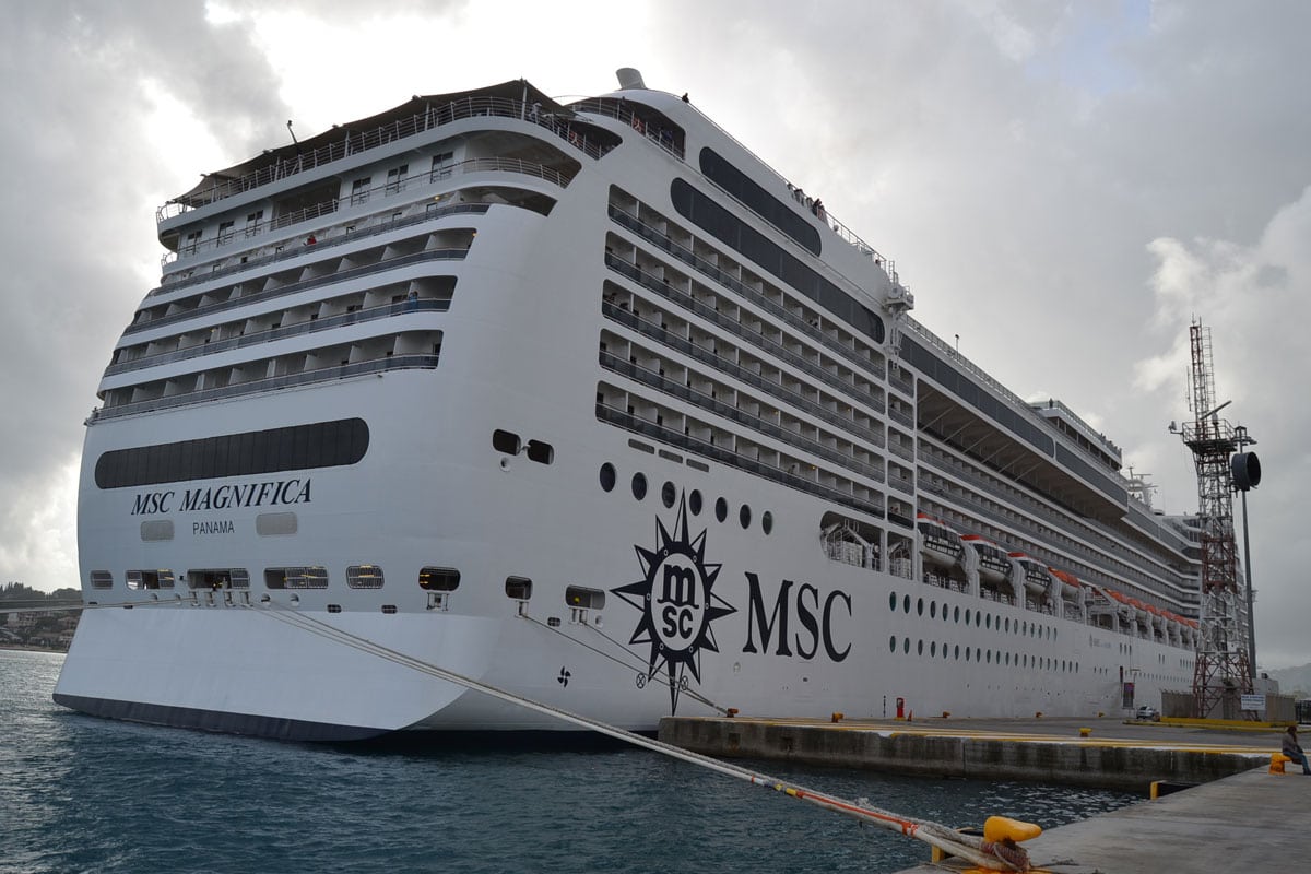 Das Kreuzfahrtschiff MSC Magnifica liegt am Pier festgemacht; der weiße Rumpf mit dem MSC-Logo ist aus der Heckperspektive bei bewölktem Himmel zu sehen.