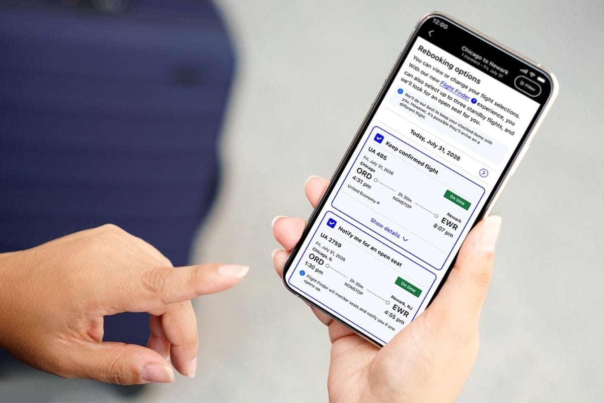 Eine Person hält ein Smartphone in der Hand, auf dessen Display eine App mit Flugumbuchungsoptionen von Chicago nach Newark für den 31. Juli 2026 zu sehen ist.