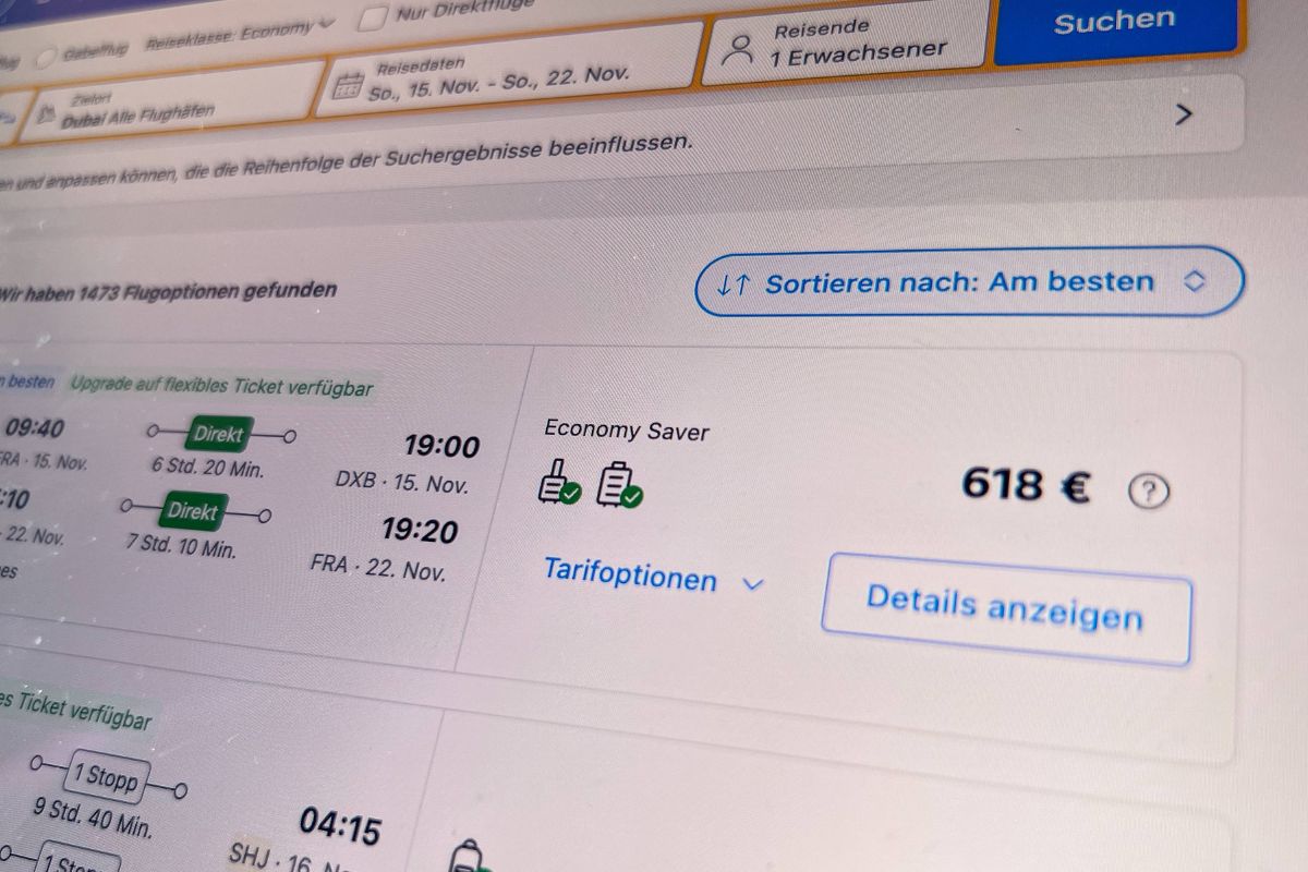 Nahaufnahme eines Bildschirms mit einer Flugsuchmaske, die Flugoptionen, Preise und Tarifdetails für eine Reise nach Dubai in der Economy-Klasse anzeigt.