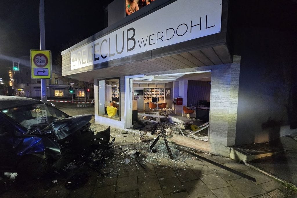 Ein bei Nacht schwer beschädigter Pkw steht vor der zerstörten Glasfront des Reiseclub Werdohl, wobei Trümmerteile auf dem Gehweg vor dem Büro liegen.