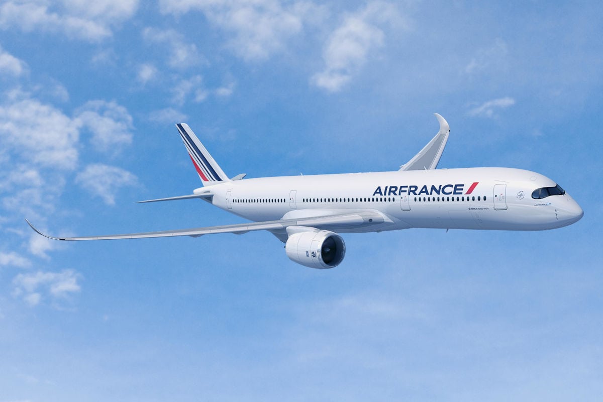 Ein weißes Passagierflugzeug vom Typ Airbus A350 der Fluggesellschaft Air France fliegt bei klarem Himmel mit leichten Wolkenformationen in der Reiseflughöhe.