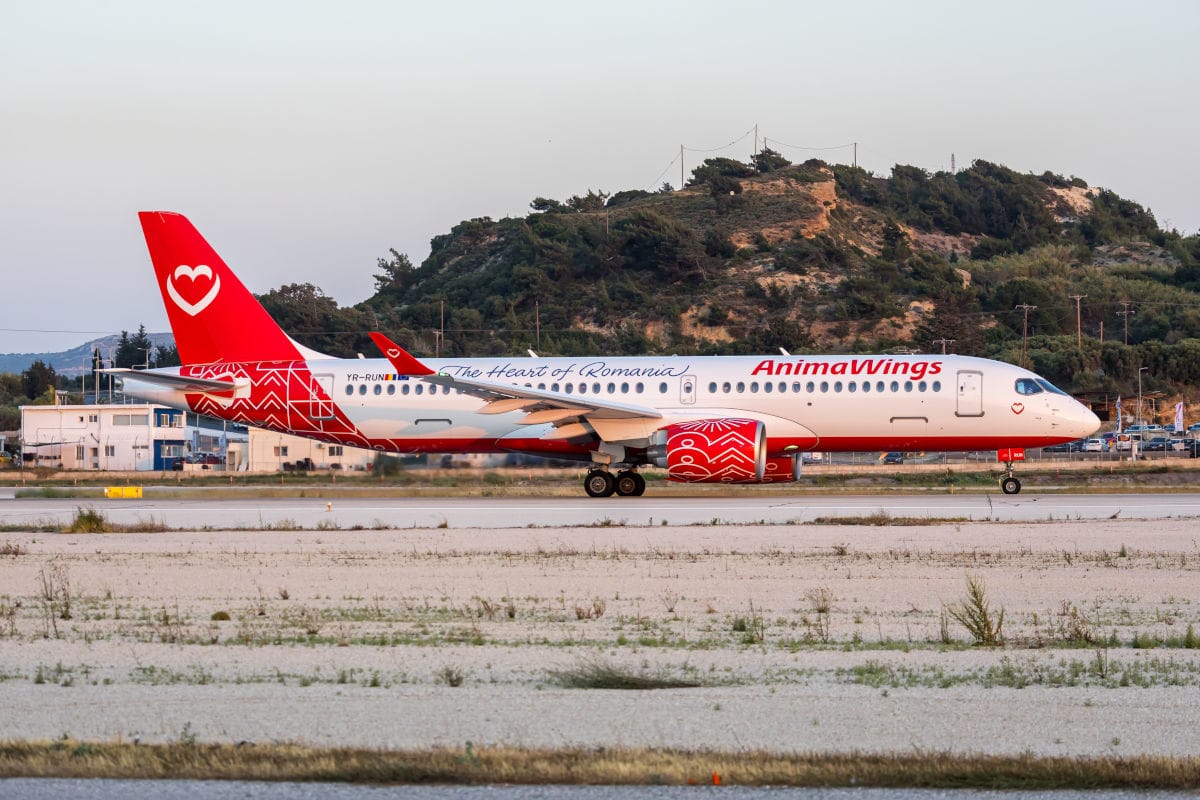 Ein Passagierflugzeug der Fluggesellschaft AnimaWings mit rot-weißer Lackierung und Herz-Logo rollt auf einer Rollbahn vor einer hügeligen Landschaft.
