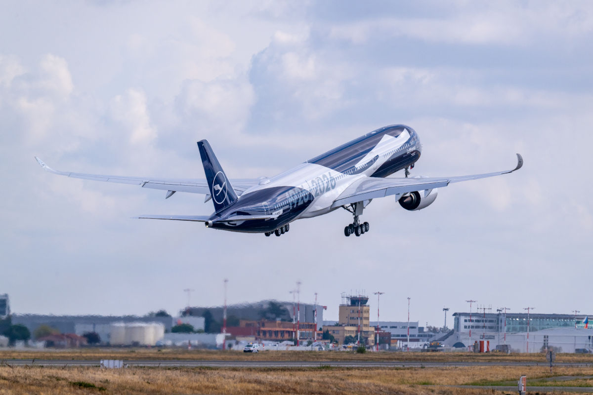Ein Lufthansa-Passagierflugzeug mit Sonderlackierung hebt von einer Startbahn ab, wobei das Fahrwerk noch ausgefahren ist und der Himmel bewölkt ist.