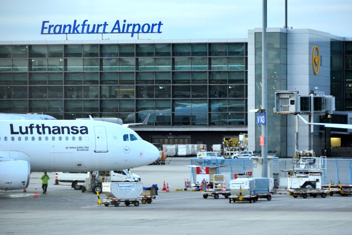 Ein Lufthansa-Flugzeug vom Typ Airbus A320-200 steht vor dem Terminalgebäude des Frankfurter Flughafens mit sichtbarem Schriftzug und Lufthansa-Logo.