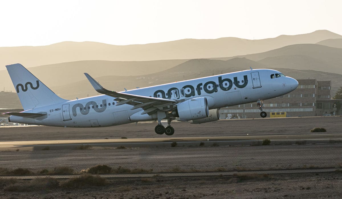 Ein weißes Passagierflugzeug der Fluggesellschaft Marabu mit dem Kennzeichen ES-MBU hebt bei Sonnenuntergang von einer Startbahn vor einer Bergkulisse ab.