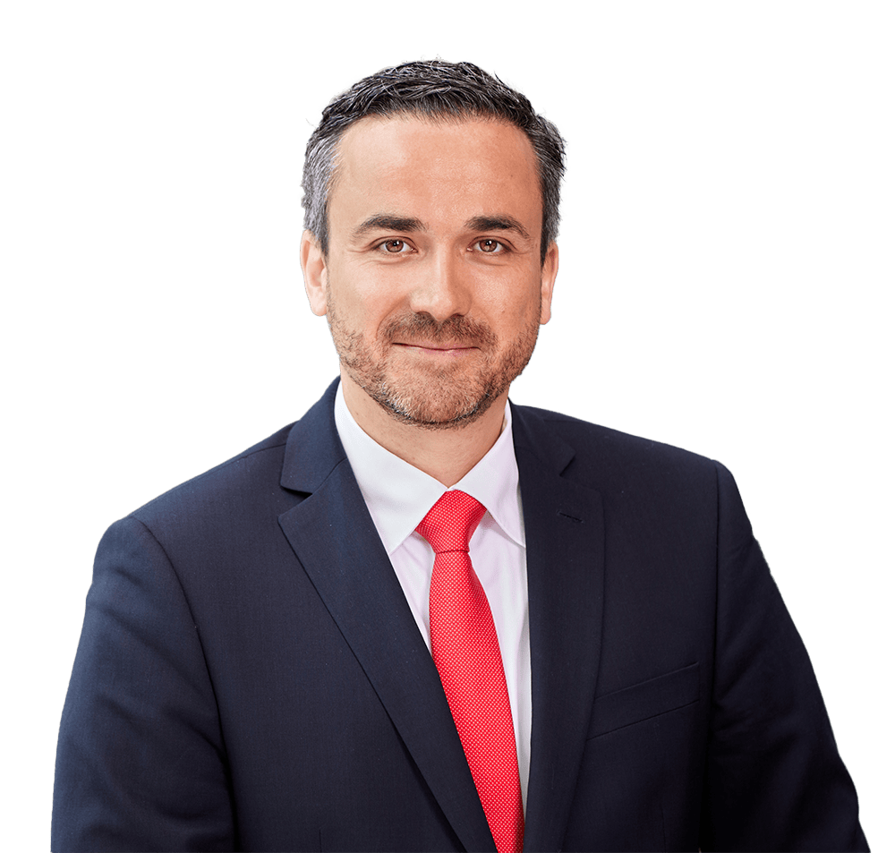 sun-express-marcus-schnabel Ein Mann mit kurzem, dunklem Haar und Dreitagebart trägt ein weißes Hemd, eine rote Krawatte und ein dunkelblaues Sakko vor einem weißen Hintergrund.