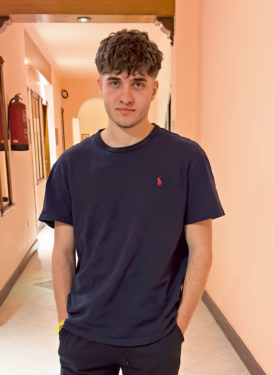 Porträt eines jungen Mannes mit schwarzem T-Shirt in einem Hausflur